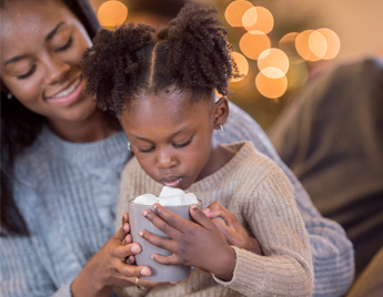 Mother sitting with young child with hot chocolate