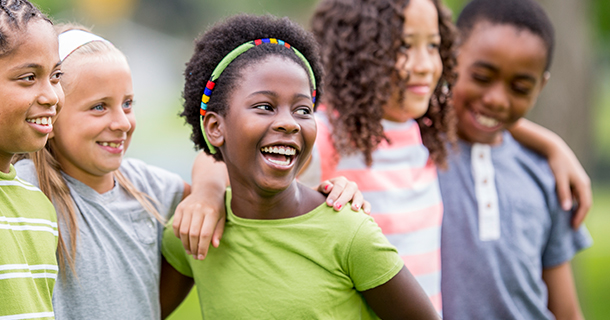 Group of young school children laughing with arms around each other