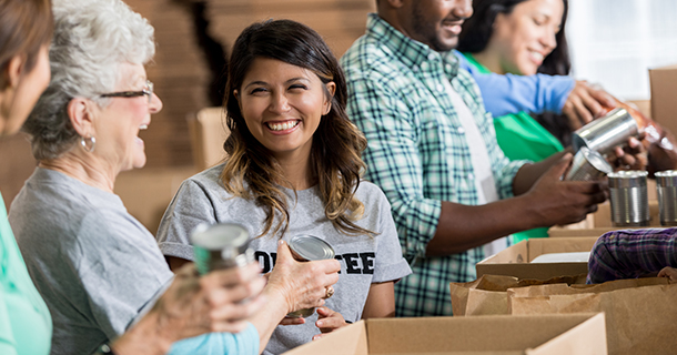 Person laughing with another person handing out boxes of canned foods