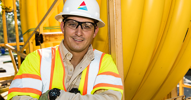 Southern Company employee in hard hat and uniform in front of yellow hoses