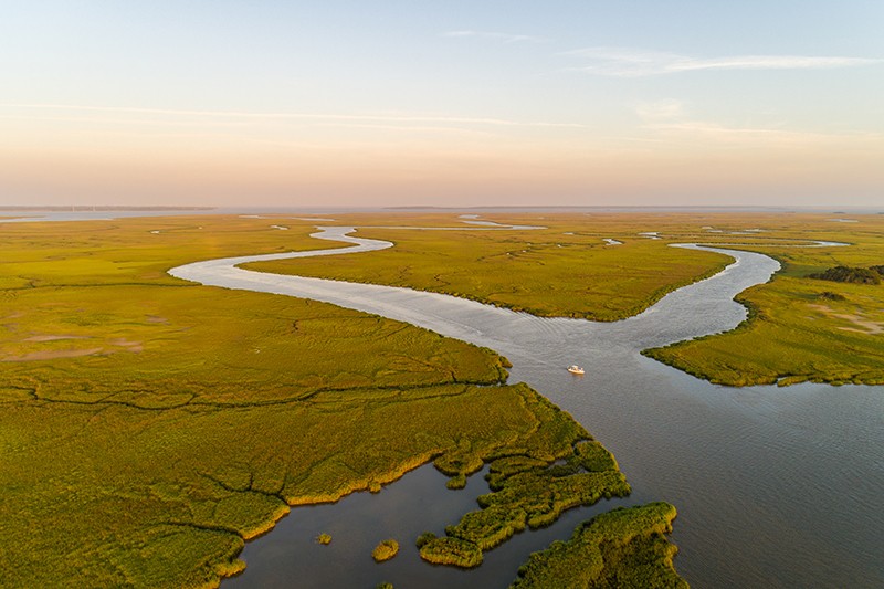 Aerial view of marsh and river just east of Brunswick, Georgia, with Saint Simons and Jekyll Islands in the distance, reflecting late-day sunlight that gives the region its "Golden Isles" nickname.