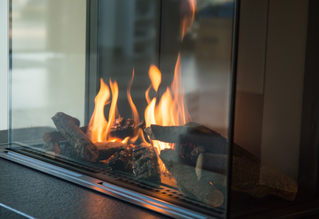 A fire burns in a glass fireplace, radiates heat